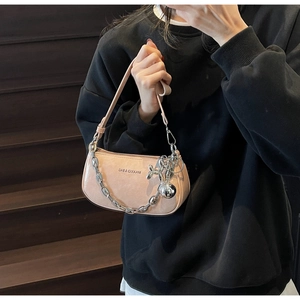 Détail d'un sac à bandoulière rose clair avec chaîne argentée et breloque chien ballon