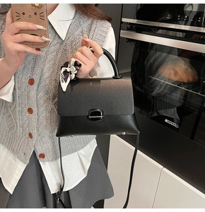 Close-up of black lychee texture leather handbag with fashion printed silk scarf detail