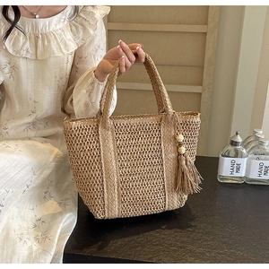 Detail of hand-woven straw tote bag with side fringe tassel and craftsmanship texture