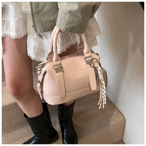 Detail of light pink soft leather Boston bag with embossed lettering and woven charm