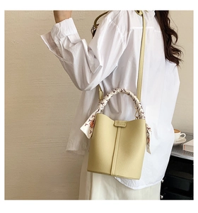 Detail of lychee pattern leather bucket bag with decorative printed silk scarf handle