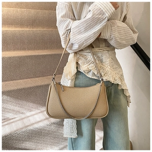 Detail of woven straw shoulder bag with adjustable leather strap and silver metal chain
