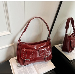 Detail of burgundy glossy underarm bag featuring silver rivets and metal buckle hardware