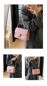 Detail of pink embossed leather crossbody bag with starry relief pattern and gold chain