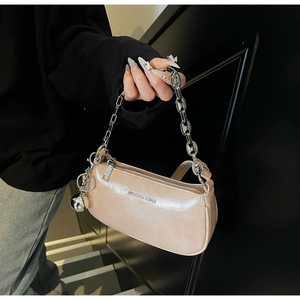 Détail du sac en cuir rose champagne brillant avec chaîne argentée et pendentif en métal
