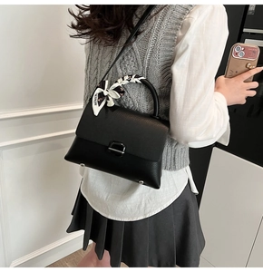 Detail of black lychee grain leather handbag featuring metal clasp and fashion silk scarf