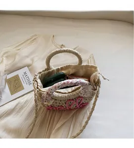 Close-up of woven straw bag showing pink hello embroidery and spacious inner drawstring pouch