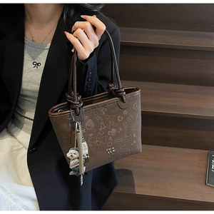 Detail of dark brown bucket bag with doodle prints and cute dog plush keychain accessory