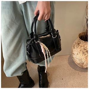 Close-up of black glossy Boston bag with silver hardware and unique ENJOY embossing