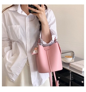 Detailed macro view of pink lychee grain leather bucket bag with decorative silk scarf
