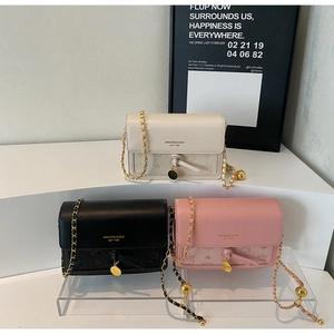 Three elegant quilted chain bags in beige, black, and pink colors displayed on a podium