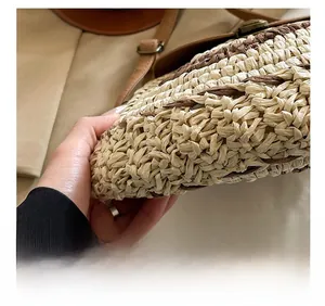 Detailed close-up showing the connection between the woven body and brown handle of straw bag
