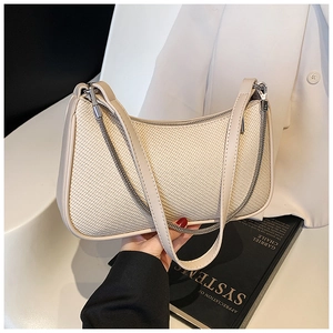 Detailed macro view of cream woven texture underarm bag with gold chain and zipper closure