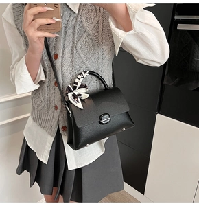Mirror selfie showing a black pebble grain leather handbag with a chic printed silk scarf