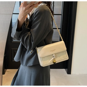 Detail view of cream white textured crossbody bag with star embossing and gold chain strap