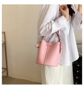 Detail view of pink bucket bag featuring lychee grain leather and silk floral scarf