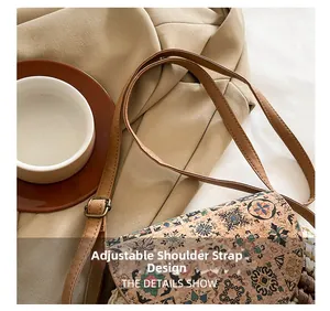 Detail showing the adjustable brown leather strap and floral ethnic pattern of the bag