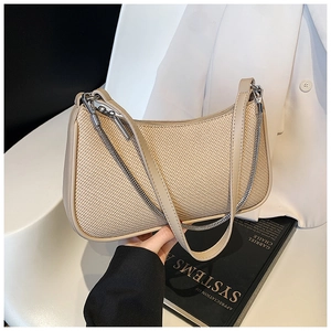 Detailed view of beige woven chain hobo bag with leather trim on a black book