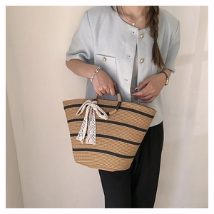 Detailed macro view of woven tote bag with contrast stripes and delicate lace bow accent