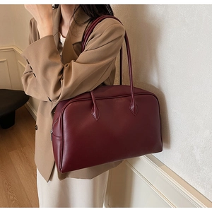 Model wearing dark red leather tote bag with silver zipper and large capacity detail
