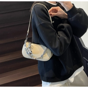 Détail du sac à bandoulière en cuir beige brillant avec chaîne argentée et boule en métal
