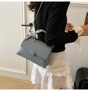 Close-up of gray-blue leather handbag with floral scarf handle and square metal lock