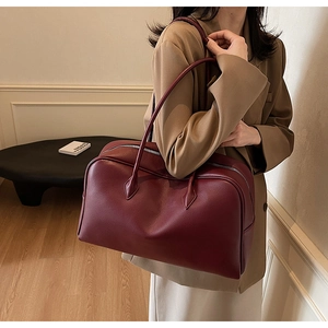 Detail of burgundy leather tote bag with lychee texture and long shoulder straps