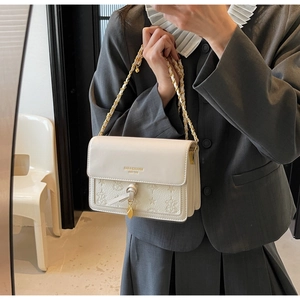 Detail of white embossed leather handbag with golden chain strap and star motifs