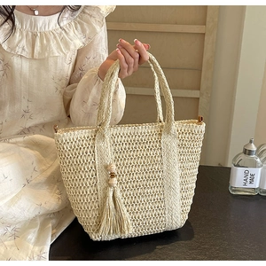Detailed view of hand-woven beige tote bag featuring wooden beads and tassel accents
