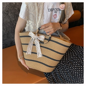 Detail of hand-woven straw basket bag featuring navy stripes and a white lace bow detail