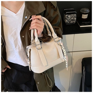 Detail of cream soft leather handbag with silver hardware and chic twill scarf accessory