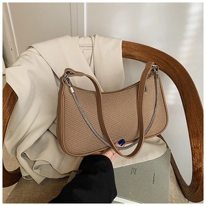 Detail of coffee brown woven baguette bag with silver chain and leather handle