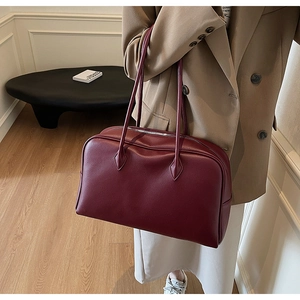 Detail view of the burgundy pebbled leather texture and long straps on a classic shoulder bag