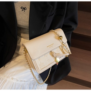 Detail of cream white leather bag with star floral embossing and gold chain strap
