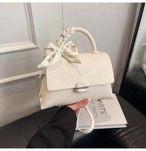 Close-up of cream white leather handbag with lychee texture and floral silk scarf detail