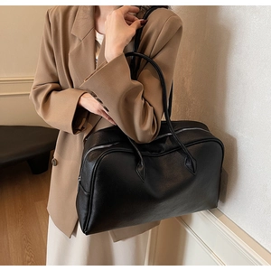 Close-up of black lychee grain leather tote bag with silver metal zipper closure
