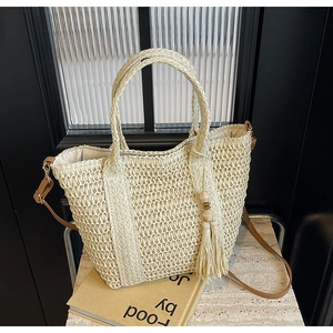 Close-up of cream woven tote bag texture featuring decorative fringe and wooden beads