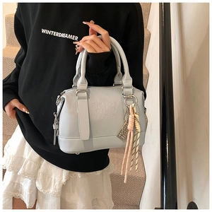 Detail of light blue faux leather Boston bag with embossed logo and knot charm accessory