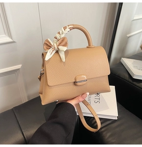 Close-up of caramel lychee grain leather handbag with decorative fashion silk scarf