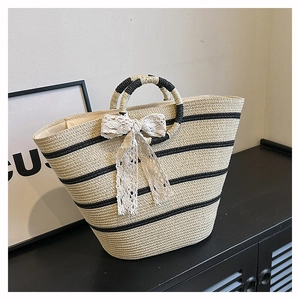Detailed macro view of woven straw tote bag with black stripes and lace bow decoration