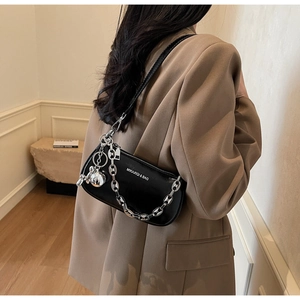 Détail du sac à épaule en cuir noir avec chaîne argentée et pendentifs décoratifs