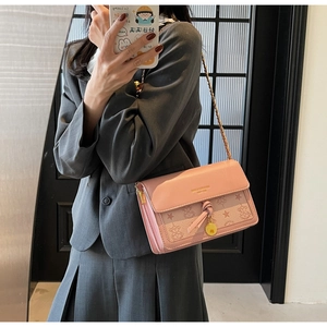 Mirror selfie showing pink embossed shoulder bag with gold chain strap and metal charm