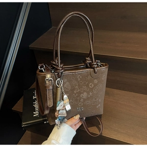 Brown bucket bag with embossed cartoon patterns and cute bear pendant on wooden stairs