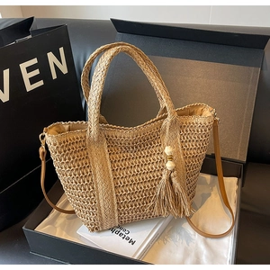Macro shot of a beige woven tote bag with wooden bead tassels and leather strap