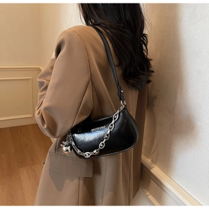 Détail d'un sac demi-lune noir avec chaîne argentée épaisse et breloque métallique