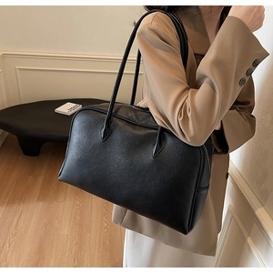 Detail showing the pebbled leather texture and slim shoulder straps of the black tote bag