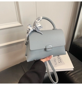 Detail of hazy blue lychee leather handbag with silk scarf handle and metal feet