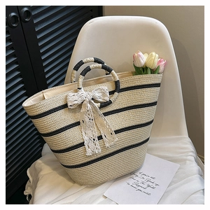 Detail of woven straw tote bag with black stripes and elegant lace bow on a chair