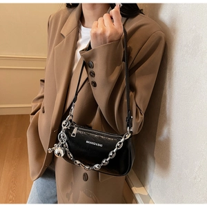 Détail du sac bandoulière noir brillant avec chaîne argentée et longue sangle en cuir
