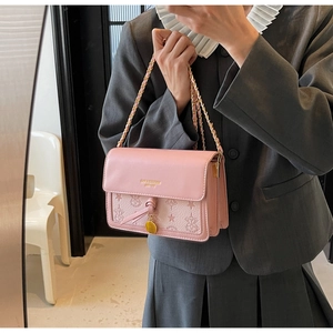 Detail of pink leather crossbody bag with star floral embossing and gold chain strap